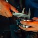 Cropped picture of a metallurgy worker measuring a bearing (metal roll cut) with a caliper. Focus on hands, work-bench setting, machine element, metal ring, milling, bored element.