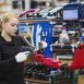 Female skilled factory worker assembling a bicycle handling the brakes assembly and part of the frame.